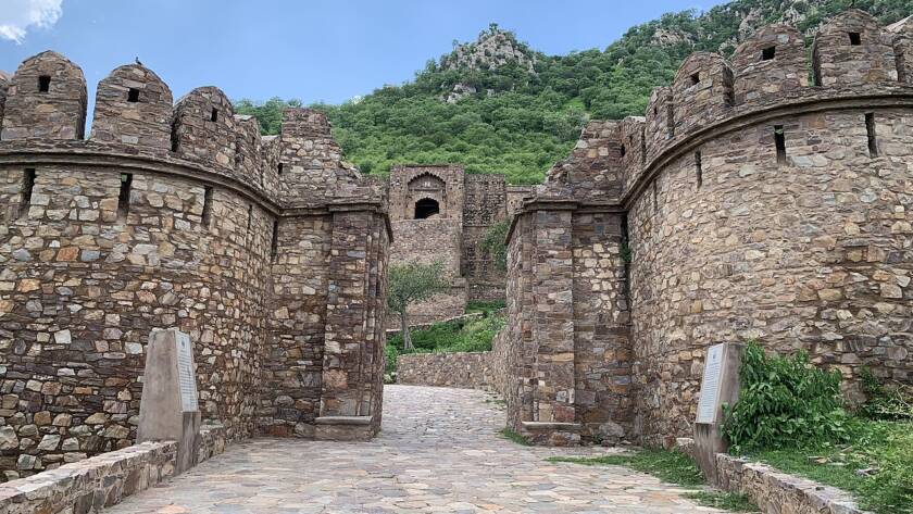 A wide view of the historic Bhangarh Fort ruins in Alwar, Rajasthan, surrounded by Aravalli hills.