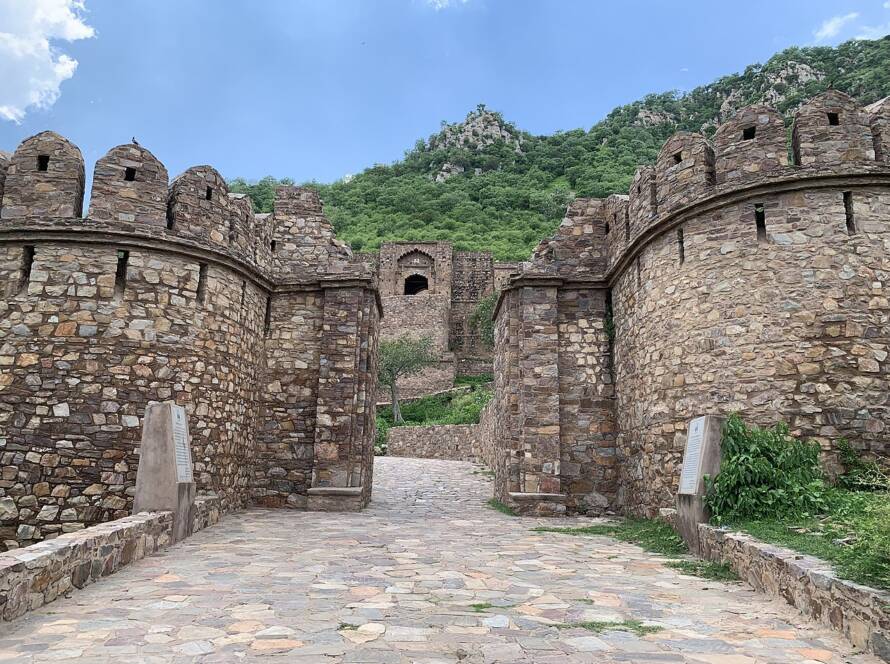 A wide view of the historic Bhangarh Fort ruins in Alwar, Rajasthan, surrounded by Aravalli hills.